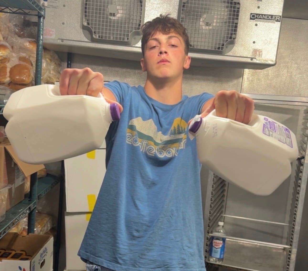 Zach Cornell flexing two gallons of milk in a restaurant walk-in cooler